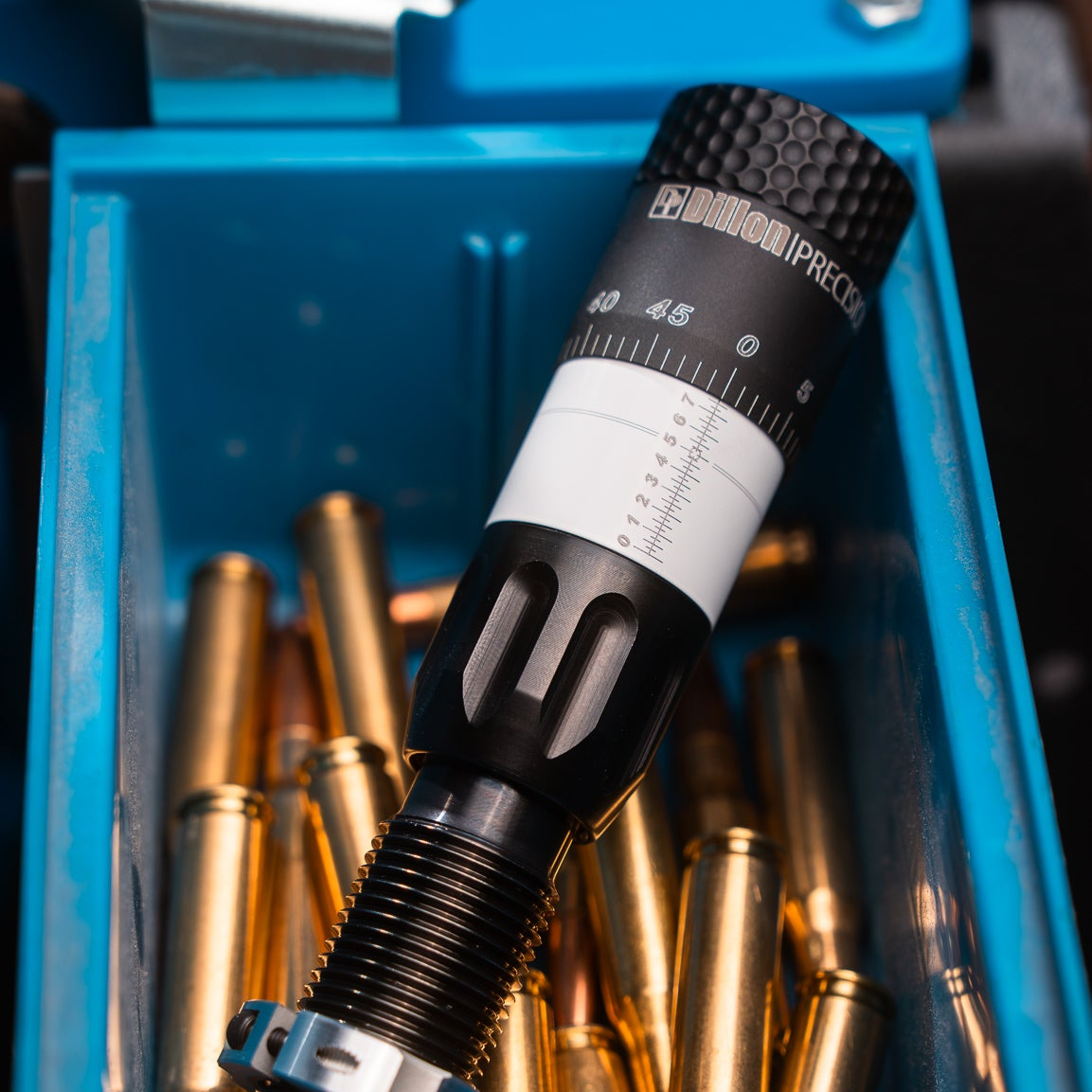The die resting in the blue parts bin of an RL550 alongside loaded rifle cartridges.